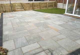 A full rear landscape involving retaining wall using sleepers, patio using a charcoal edging pavior, a kandla grey indian sanstone and grass area returfed at a job in Gedling, Nottingham A full rear landscape involving retaining wall using sleepers, patio using a charcoal edging pavior, a kandla grey indian sanstone and grass area returfed at a job in Gedling, Nottingham